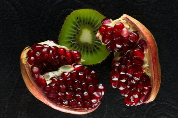 Ripe and juicy pomegranate and kiwi fruit close-up on a black background.