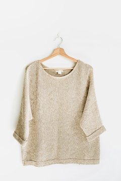 Female pullover on hanger at white wall. Woman fashion clothes concept.