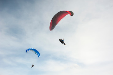 Two paragliders flying in the blue sky against the background of clouds. Paragliding in the sky on a sunny day.