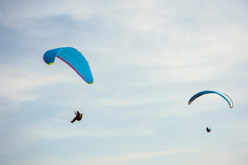 Two paragliders flying in the blue sky against the background of clouds. Paragliding in the sky on a sunny day.