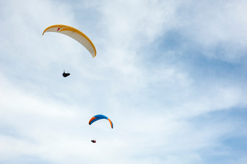 Two paragliders flying in the blue sky against the background of clouds. Paragliding in the sky on a sunny day.