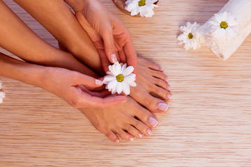 Obraz na płótnie Canvas The picture of ideal done manicure and pedicure. Female hands and legs in the spa spot.