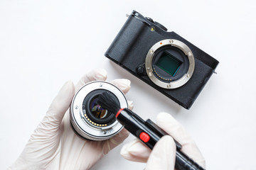 Close-up of mirrorless digital APS-C dirty camera matrix sensor cleaning and maintenance with swab, photographer cleaning photocamera on white background
