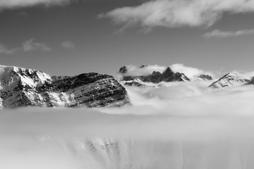 Snowy sunlight mountains in haze and cloudy sky at nice sun day