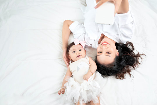 Woman with a baby doing a selfie lying on wooden floor