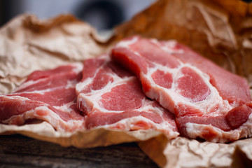 Fresh raw sliced meat on cooking paper and wooden table.
