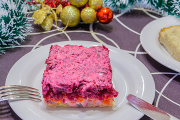 Dressed herring or herring under a fur coat. Symbol of the new year. Traditional Russian cuisine. Christmas decorations in the background. New Year's concept.