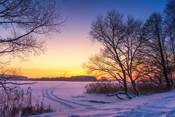 Colorful winter sunset with frozen lake and sunset sky.