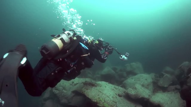 Scuba diver cameramen on background of reflection of sunlight in Lake Baikal.