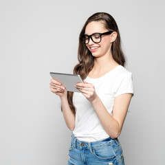 Portrait of happy female student wearing glasses, using digital tablet