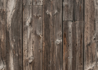 Old weathered wood plank siding with lots of texture from grain, knots, and nail holes.