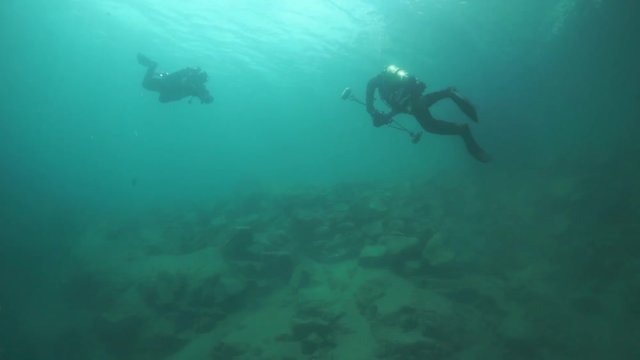 Scuba diver cameramen swimming deep underwater in Lake Baikal.