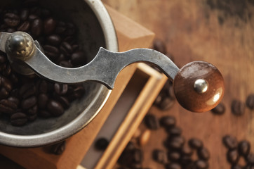 Old vintage coffee grinder with grains of coffee on a wooden table. retro style.  Copy-space. selective focus.