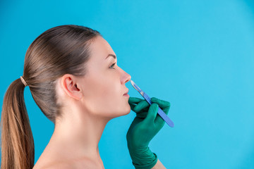 Cosmetic surgeon examining female client in office. Doctor checking woman's face, the nose before plastic surgery. Surgeon or beautician hands touching woman face. Rhinoplasty