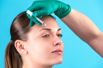 Fototapeta premium Beautiful woman face and beautician hands with syringe. Doctor makes cosmetic injection. Clean Beauty concept