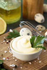 Mayonnaise Sauce close-up. Homemade mayonnaise sauce in a white bowl on black stone or concrete background.