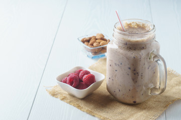 Blueberry raspberry smoothie on a blue background with a cup of raspberry and almond