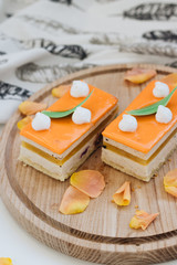 Fototapeta na wymiar Two pieces of delicious cake on wooden board decorated with floral petals