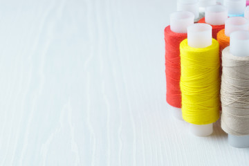Multicolor sewing threads on wooden table, side view