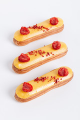 Set of delicious eclairs with yellow glaze and raspberries	