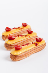 Set of delicious eclairs with yellow glaze and raspberries	