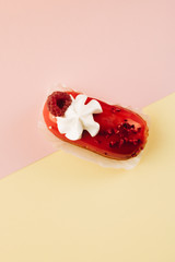 Delicious eclair with red glaze and raspberry, sweet dessert