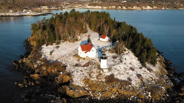 Close up Aerial ORBIT over a snow covered Curtis Island Lighthouse at sunrise with long shadows in the snow