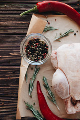 Raw chicken, pepper and fresh herbs on wooden table ready for cooking 