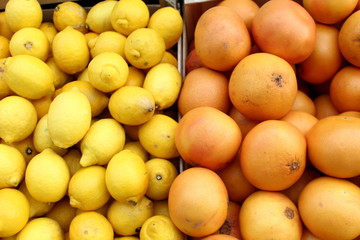 Many yellow shining organic lemon and oranges  on market light background pattern