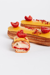 Set of delicious eclairs with yellow glaze and raspberries