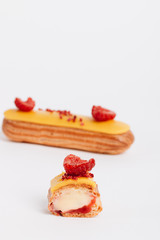 Set of delicious eclairs with yellow glaze and raspberries
