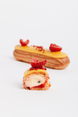 Set of delicious eclairs with yellow glaze and raspberries