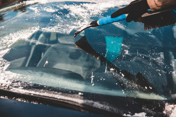 Frozen window. Removing ice from car`s front glass with scraper