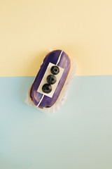 Delicious eclair with violet glaze and bluberries, sweet dessert