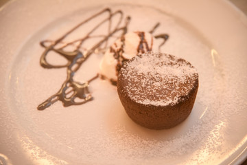 Chocolate muffins with chocolate syrup and ice cream .