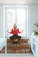 Beautiful young woman resting by window at home