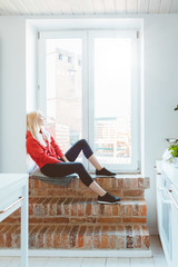 Beautiful young woman resting by window at home