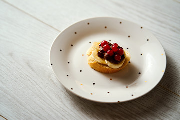 plate with a sweet version of mini tapas with banana chocolate and currant on a light wooden table