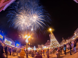 Christmas and New Year celebration in central square of Brasov town, with decorated tree and fireworks on the sky.