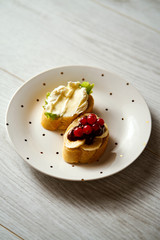 plate with a vegetarian mini-sandwich set with brie cheese, currant lettuce, chocolate and banana on a wooden table