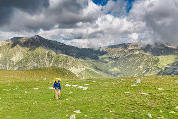 Fototapeta na wymiar Happy woman hiker travels in Pyrenees Mountains in Andorra and Spain. Nordic walking, recreation and trekking along GR11 path trail