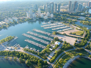 Aerial bird eye shot over Humber Bay Shores Park, Toronto, Canada with coastal condo homes, blue skies, beaches and harbour entrance in view with glass condominiums. Perfect summer day sunset.