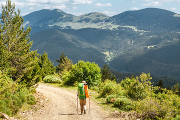 Fototapeta na wymiar Happy woman walking with backpack in Pyrenees mountains Highlands