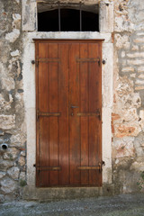 Old brown wooden front doors on old stone house.