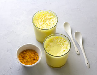 Golden milk with turmeric in a glass on a gray stone background. healthy natural energy drink. selective focus