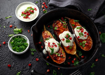 Grilled eggplants with yogurt sauce, pomegranate seeds, parsley and green onion in cast iron...