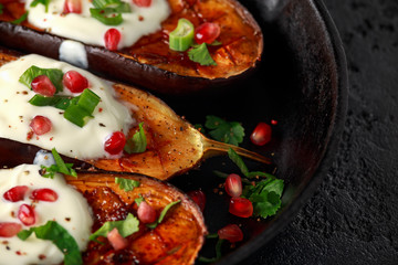 Grilled eggplants with yogurt sauce, pomegranate seeds, parsley and green onion in cast iron vintage pan.