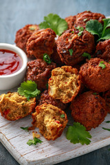 Indian Pakora snack spicy onion, red pepper with chilli sauce on white wooden board