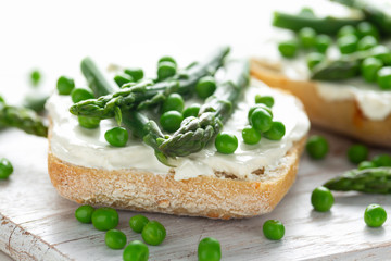 Appetizer bruschetta, toast with Asparagus, Peas and creamy soft cheese. on white board.