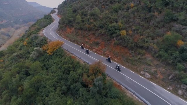 Epic and inspiring aerial drone shot of motorcycle club friends or crew gang drive on small winding mountain road. Bikers weekend getaway adventure. Amazing wanderlust exploration and travel vibes